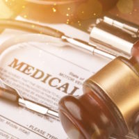 Medical malpractice forms, wooden gavel and stethoscope, close-up view