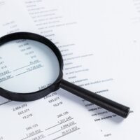 Magnifying glass on financial statement paper. Analyzing business financial data.
